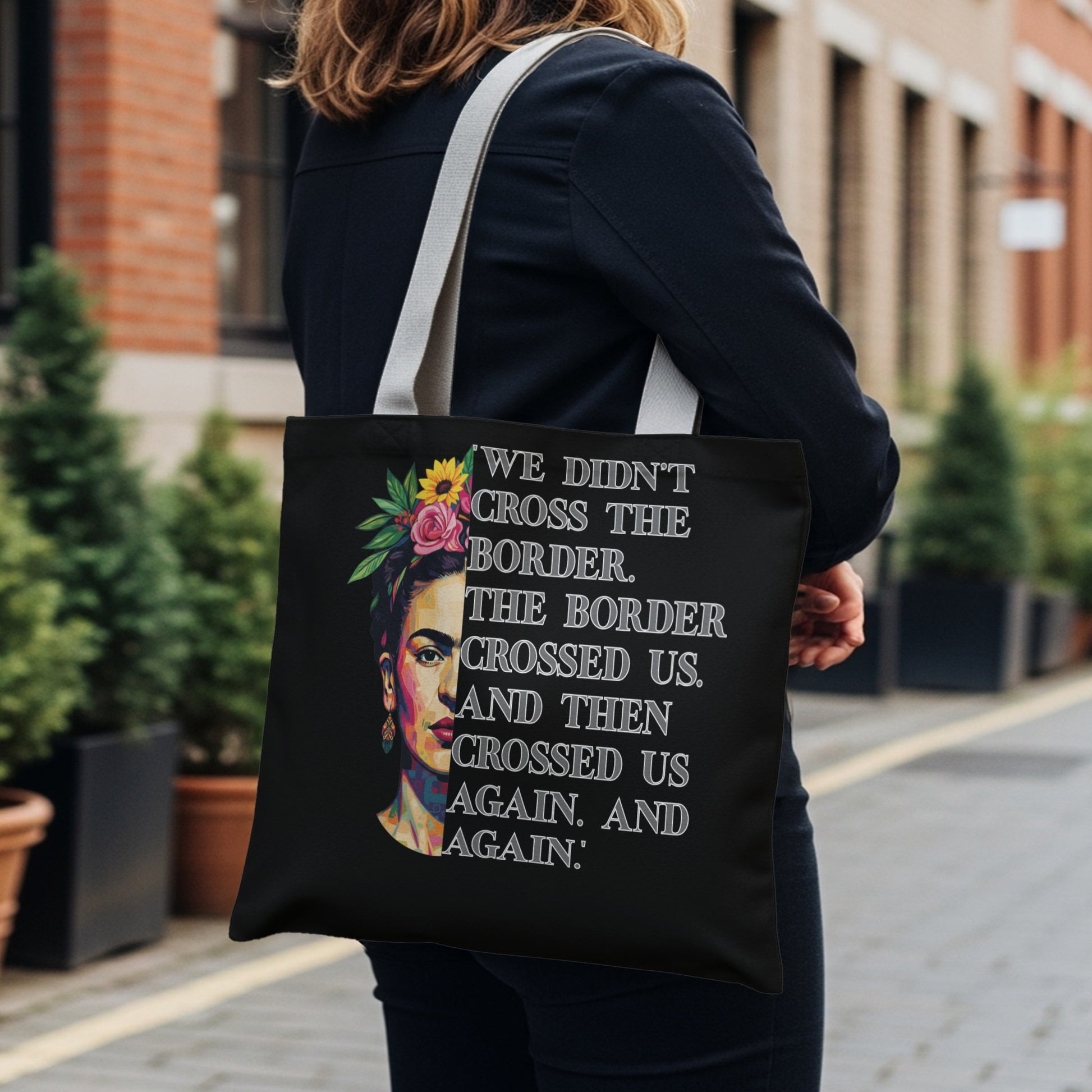 Black tote bag featuring Frida Kahlo portrait and quote about crossing borders.