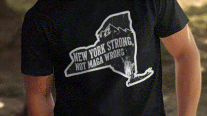 A black t-shirt with a graphic design on the back, depicting a map of New York State with the text "NEW YORK STRONG, NOT MAGA WRONG!" printed on it.