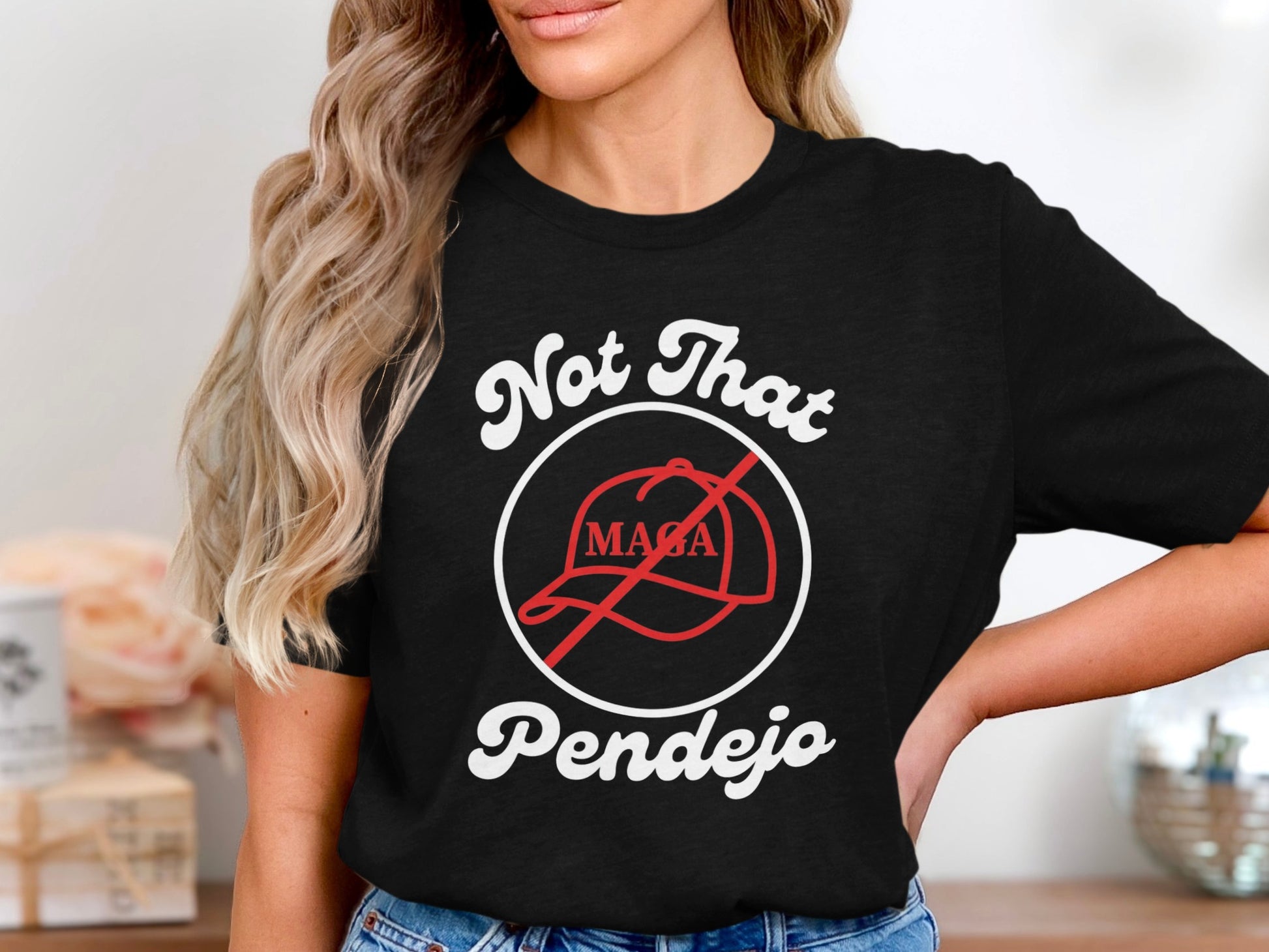 Black t-shirt with white text "Not That Pendejo" and a red circle with a line through a MAGA hat.