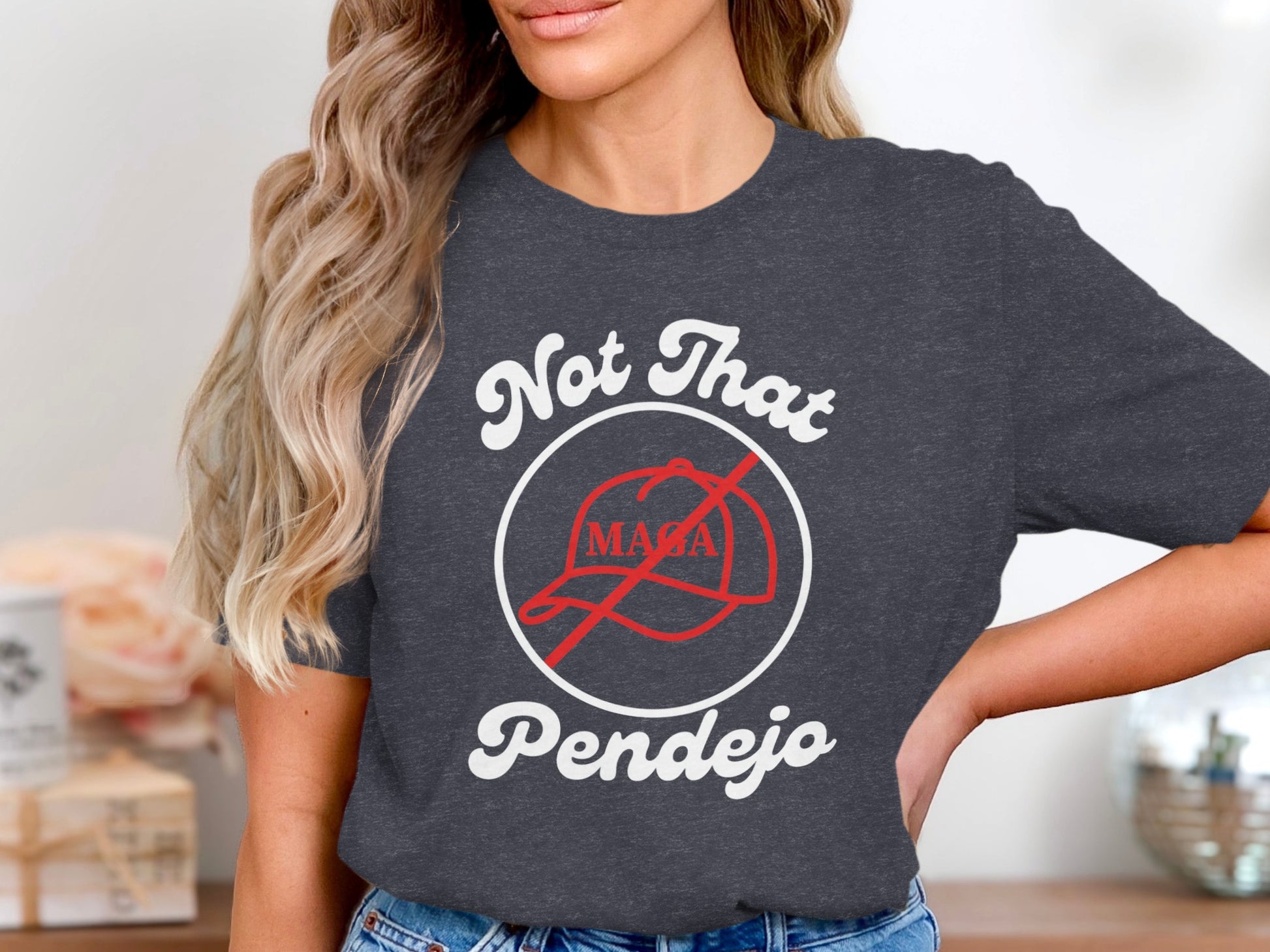Dark grey t-shirt with white text "Not That Pendejo" and a crossed-out red baseball cap.