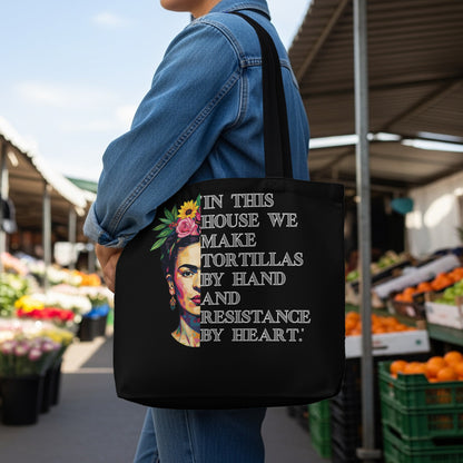 Tote bag with Frida Kahlo portrait and "In this house we make tortillas by hand and resistance by heart" text.