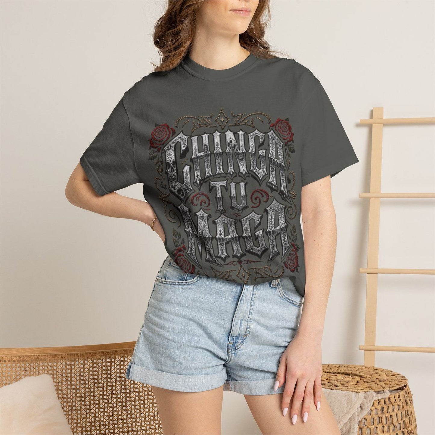 A woman wearing a gray t-shirt with a graphic design and denim shorts stands in front of a wooden ladder.