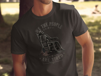 T-shirt with skeleton in rocking chair, American flag, and text "We The People Are Tired".