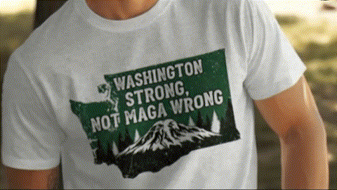 A person wearing a white t-shirt with a graphic design that says "WASHINGTON STRONG, NOT MAGA WRONG" in green and white text.