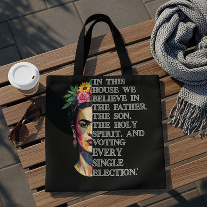 Black tote bag featuring Frida Kahlo's portrait and "In this house we believe in the Father, The Son, The Holy Spirit, and voting every single election."