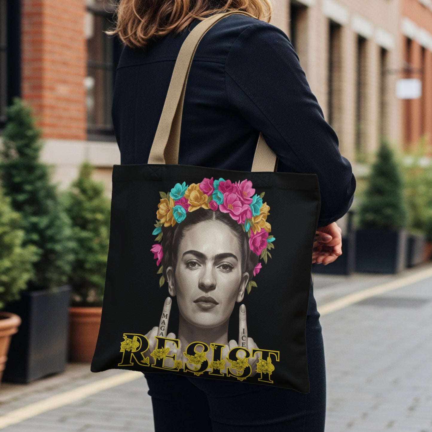 Frida Kahlo tote bag with colorful floral crown, pointing to "Resist" text.