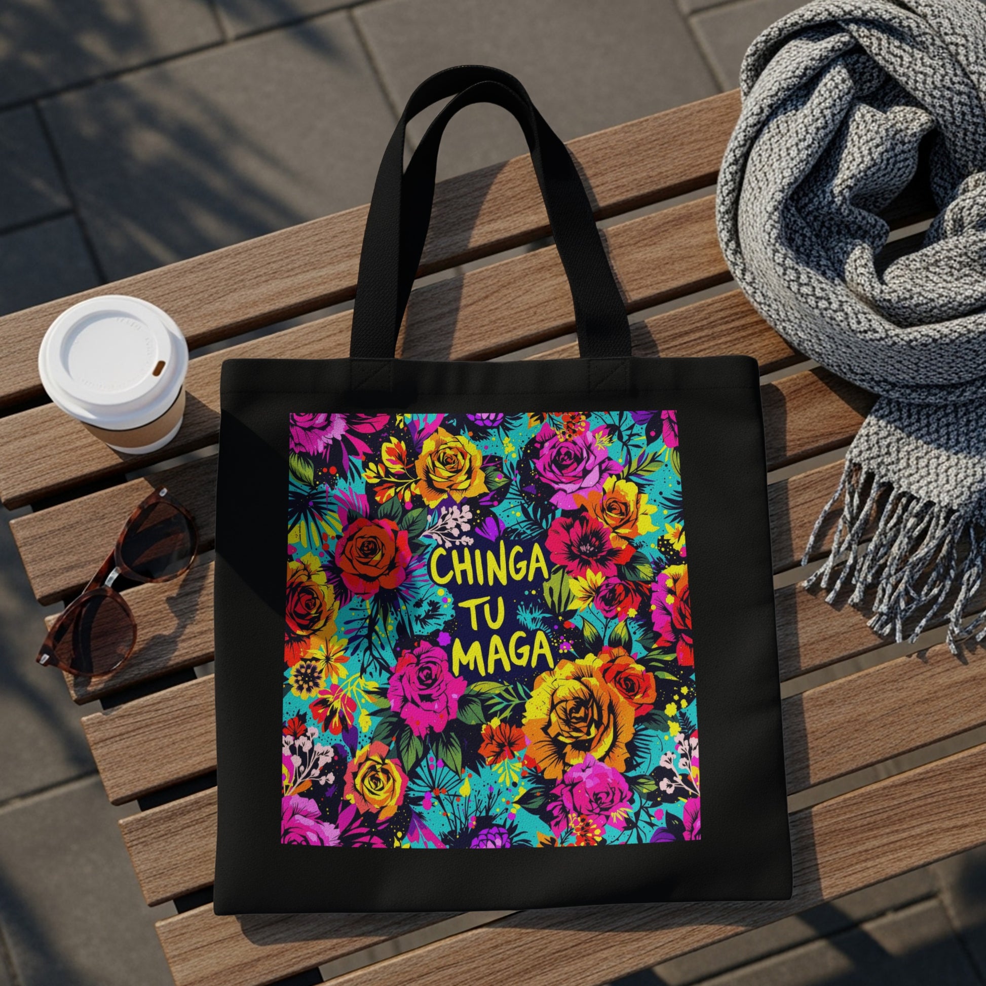 Black tote bag with vibrant floral print and "CHINGA TU MAGA" text.
