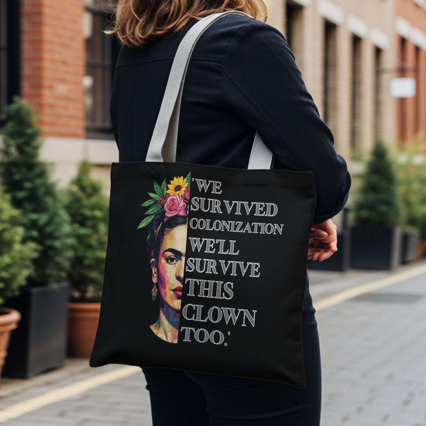 Black tote bag with Frida Kahlo portrait and quote: "We survived colonization. We'll survive this clown too."