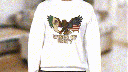A person wearing a white sweatshirt with an embroidered design of an eagle and the text "WINGS OF UNITY" printed on it.