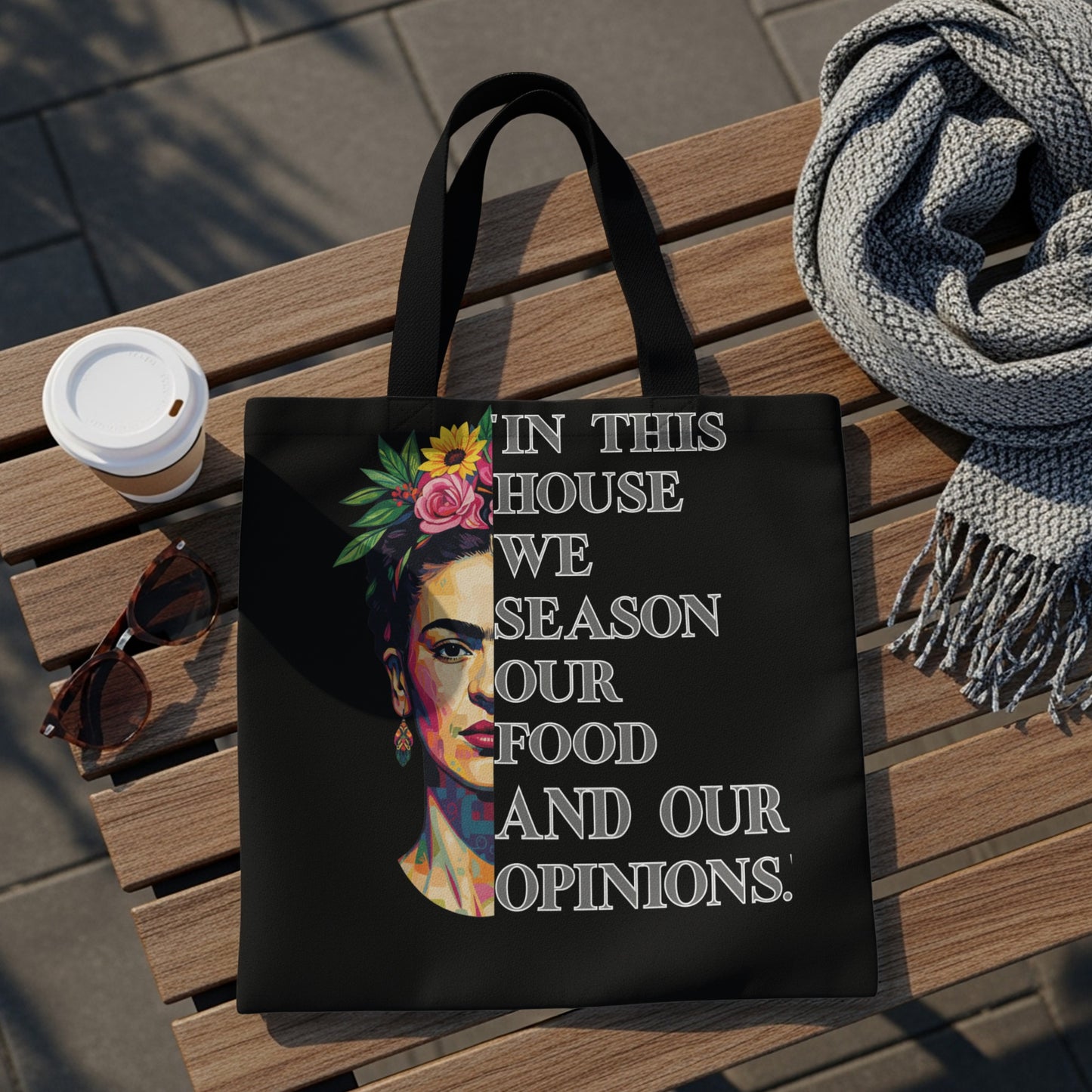Black tote bag with Frida Kahlo portrait and text "In this house we season our food and our opinions."