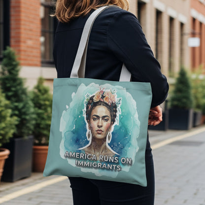 Tote bag featuring a watercolor portrait of Frida Kahlo with flowers, text reads "America Runs On Immigrants".