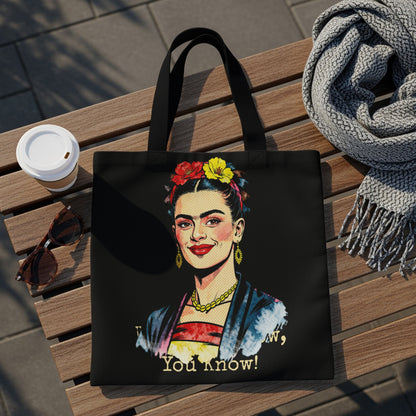 Black tote bag featuring a portrait of Frida Kahlo with colorful flowers and text.