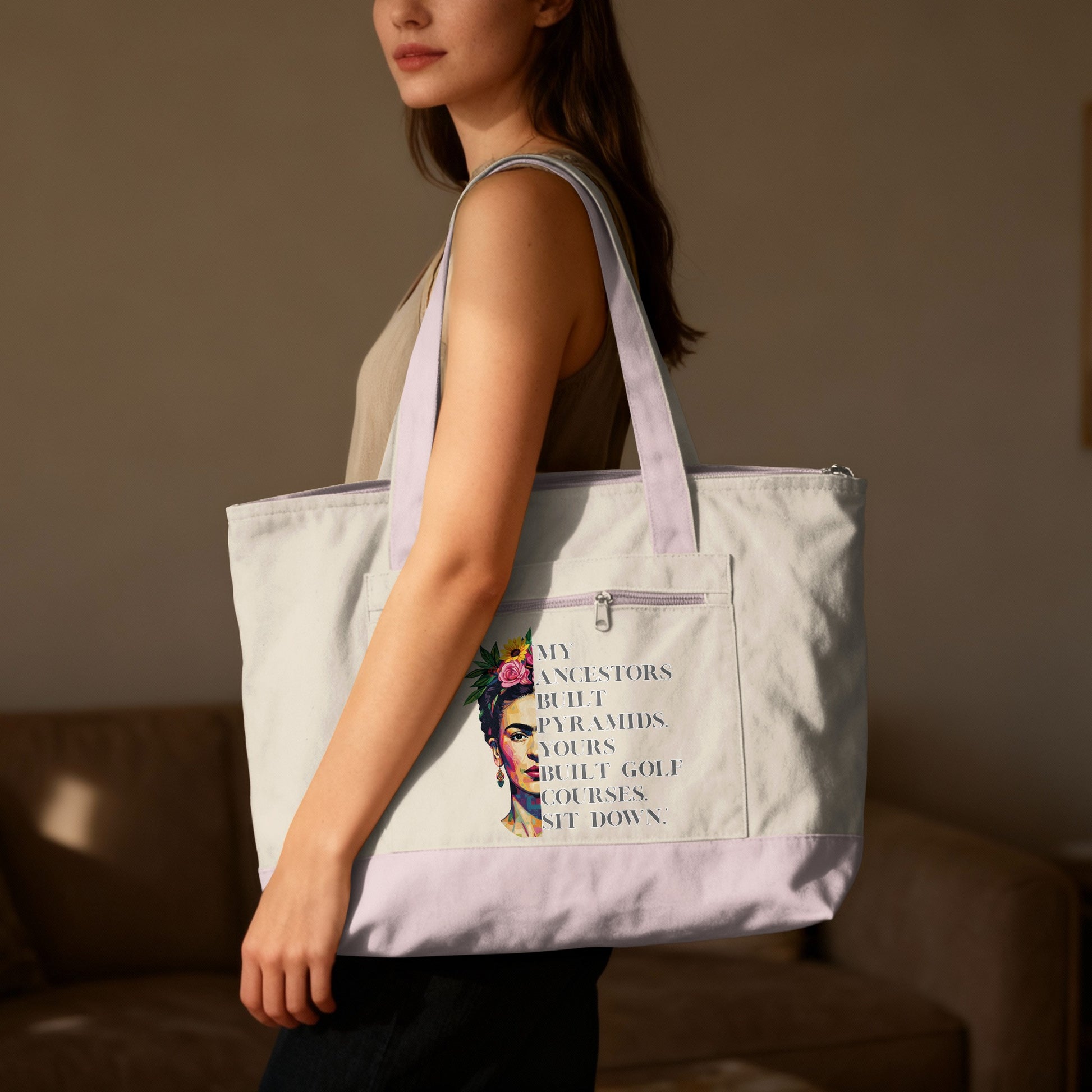 Woman holds Frida Kahlo tote bag with text "My ancestors built pyramids. Yours built golf courses. Sit down."