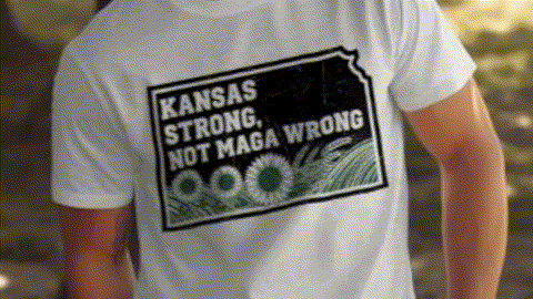 A person wearing a white t-shirt with a graphic design that says "KANSAS STRONG, NOT MAGA WRONG".