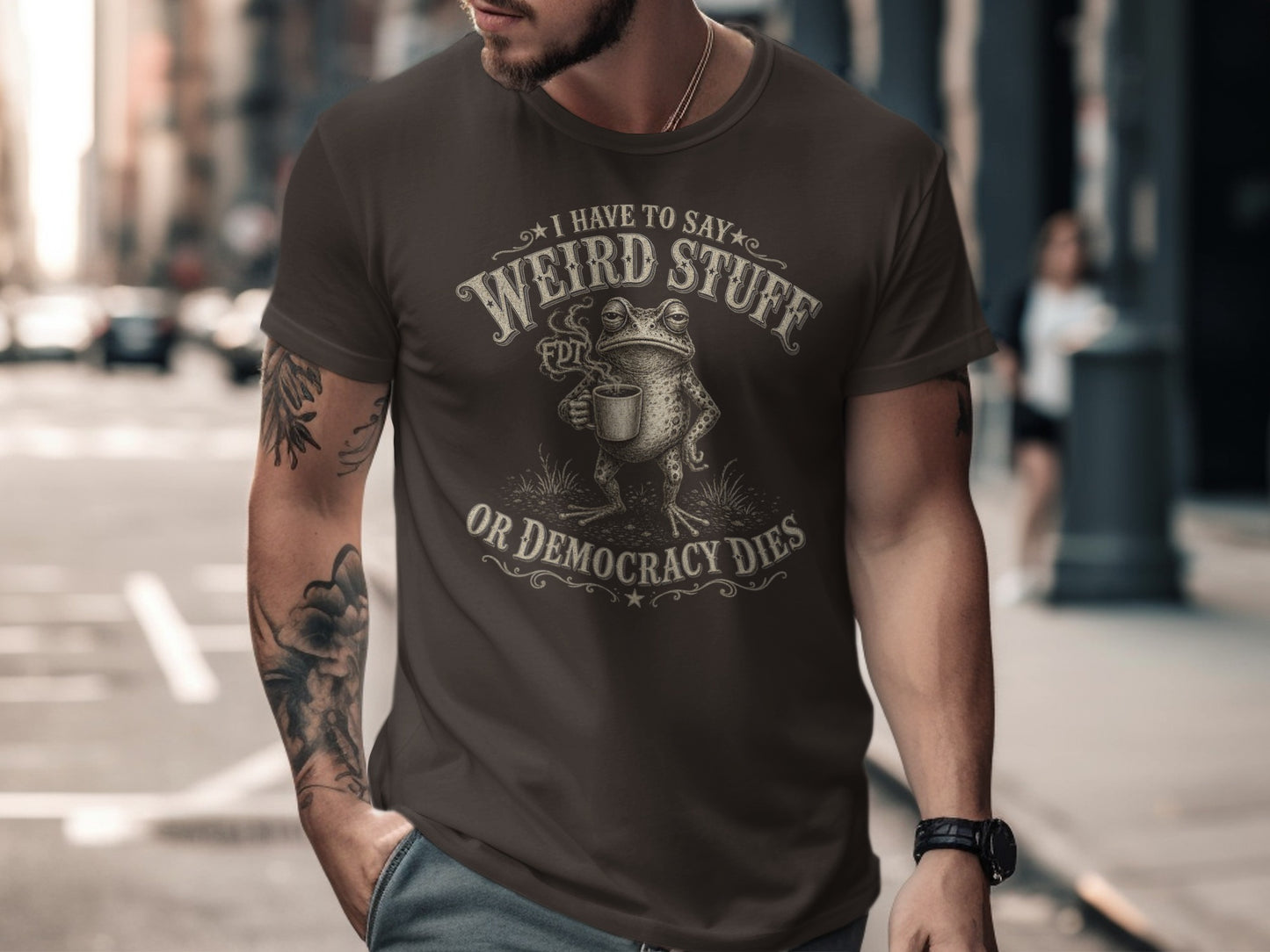 Brown t-shirt with frog holding coffee, "I have to say Weird Stuff or Democracy Dies" text.