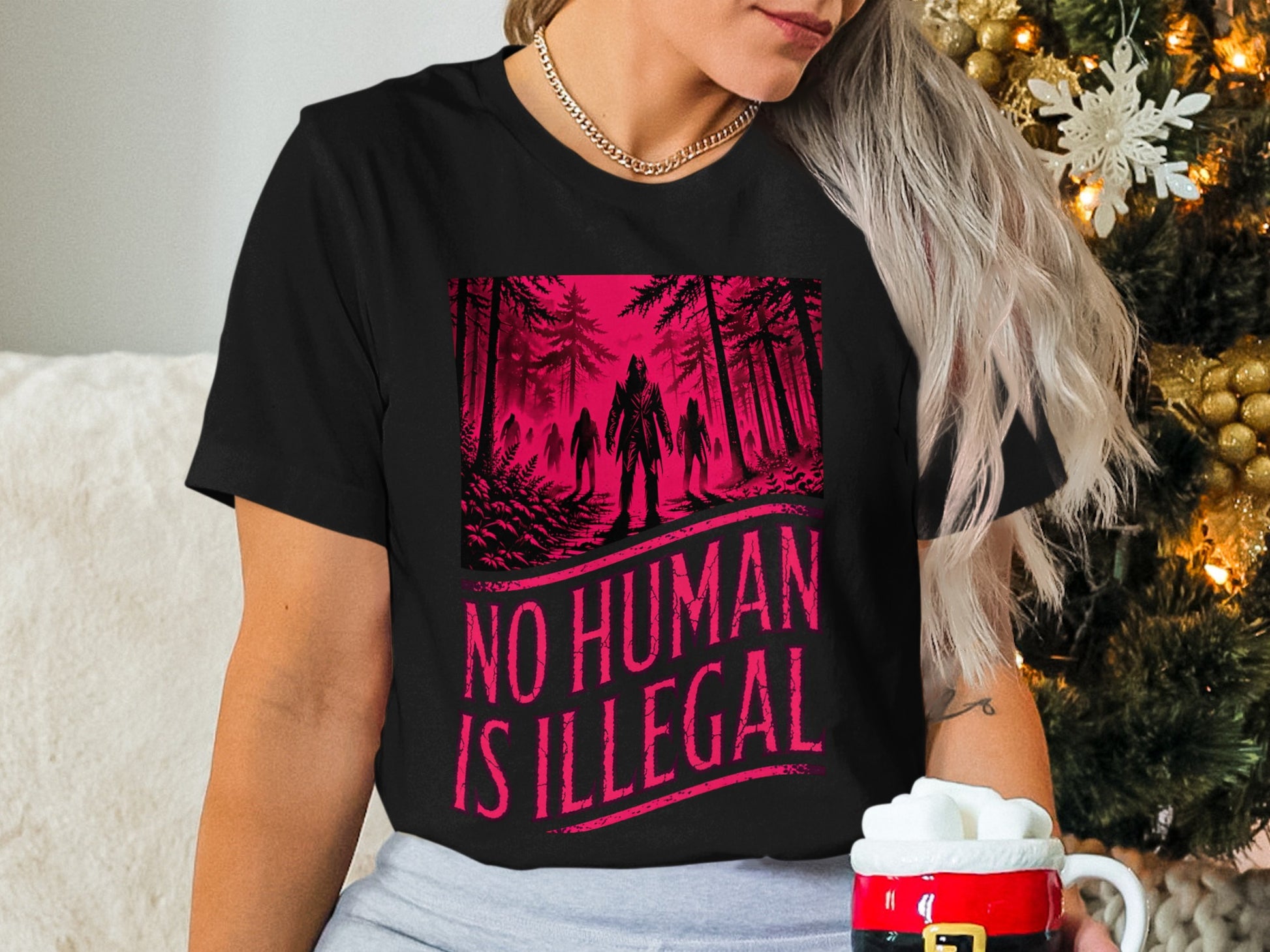 Black t-shirt with "NO HUMAN IS ILLEGAL" text and forest figures.