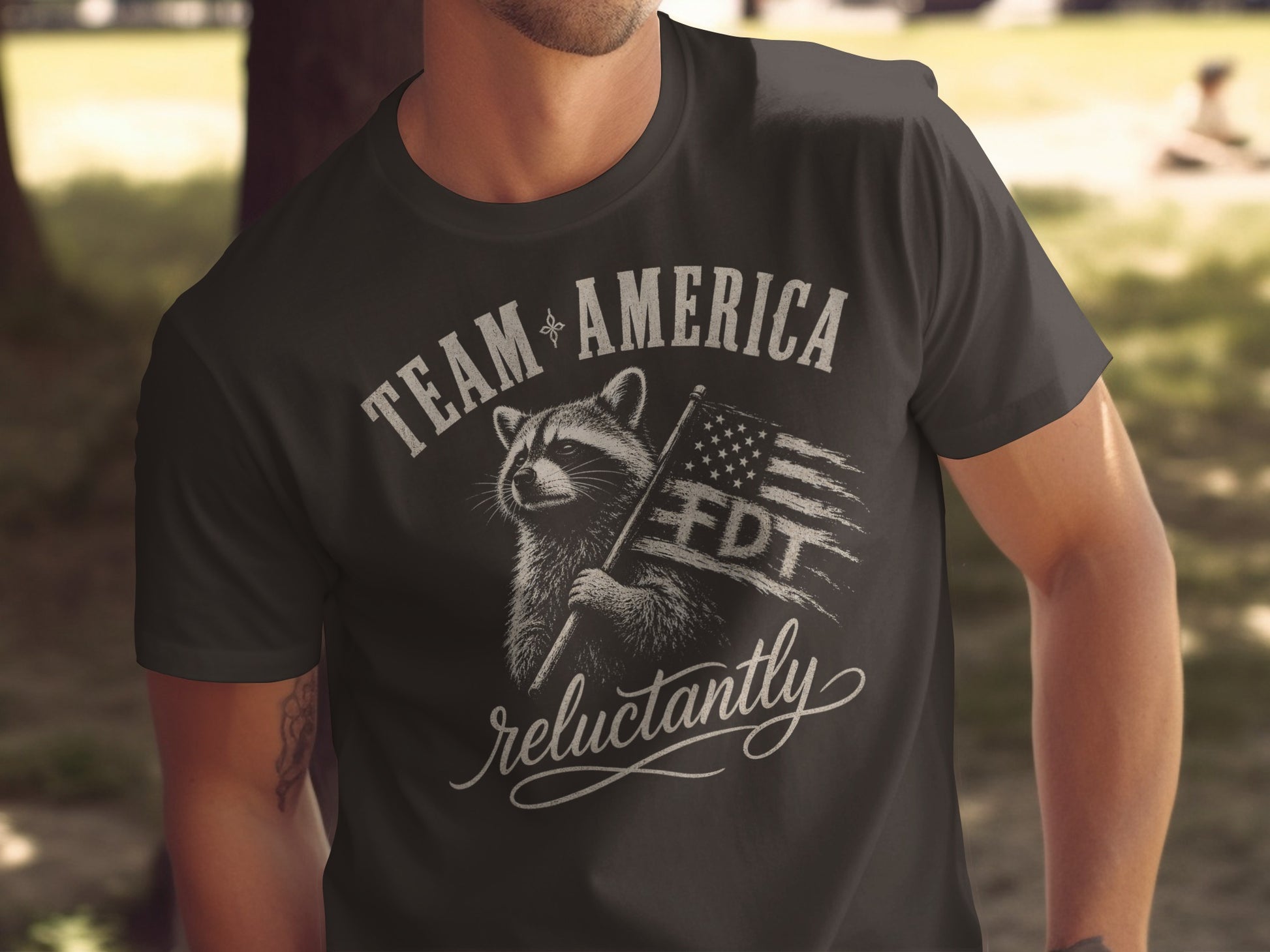T-shirt with raccoon holding American flag and text "TEAM AMERICA FDT reluctantly".