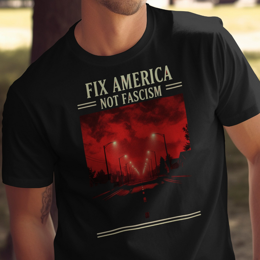 Black t-shirt with white text "FIX AMERICA NOT FASCISM" over a dark, eerie street scene.
