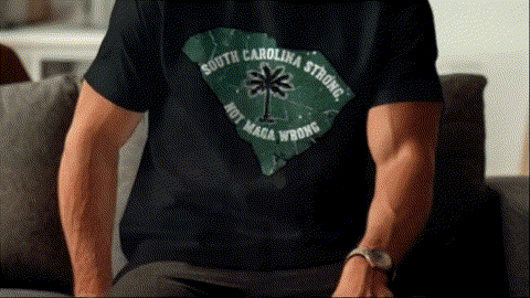 A person wearing a black t-shirt with a graphic design on the back, sitting on a couch.