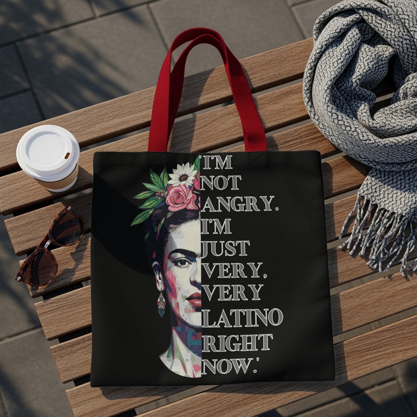 Black tote bag with red handles, featuring Frida Kahlo portrait and "I'm not angry. I'm just very, very latino right now." text.