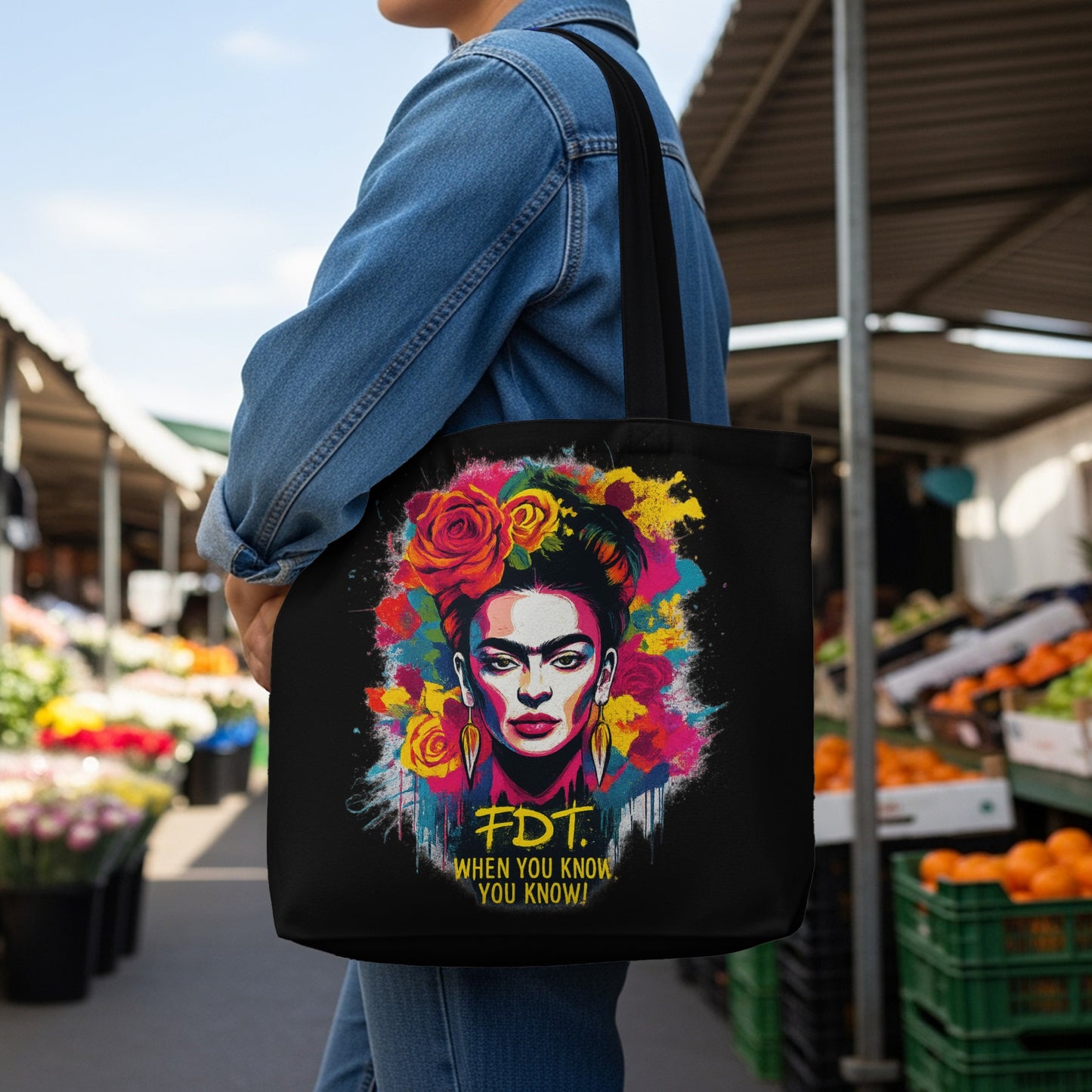 Black tote bag with Frida Kahlo portrait, floral accents, and text.