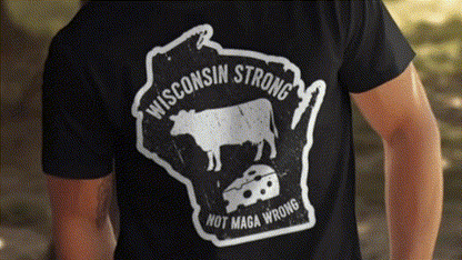 A black t-shirt with a graphic design featuring a cow and a piece of cheese, along with the text "Wisconsin Strong" and "Not Maga Wrong".