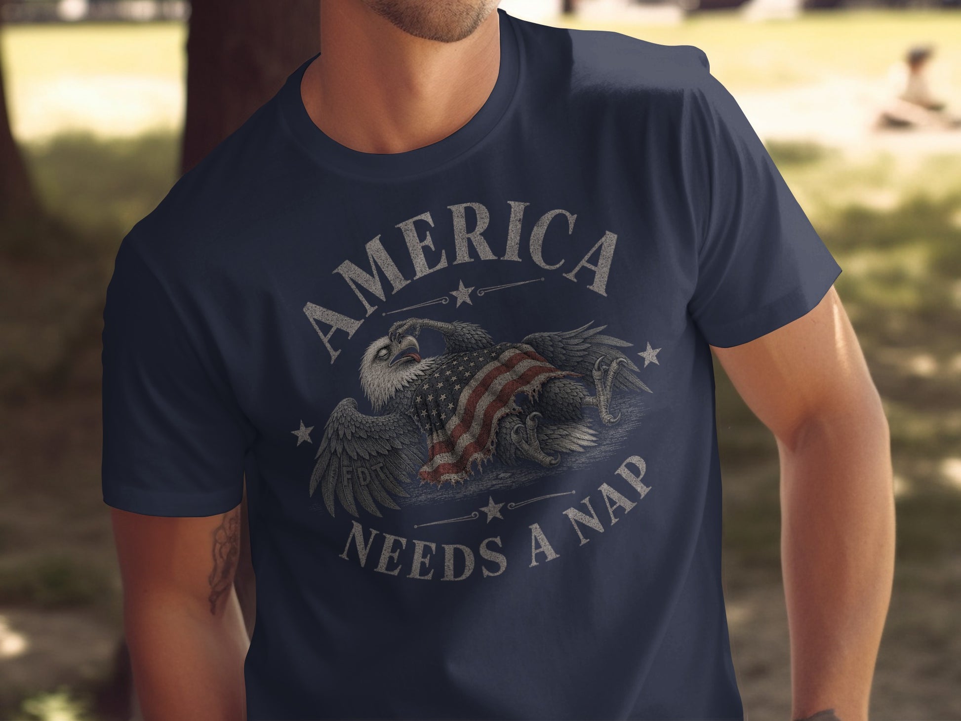 Navy t-shirt with distressed eagle and American flag design, text reads "AMERICA NEEDS A NAP".