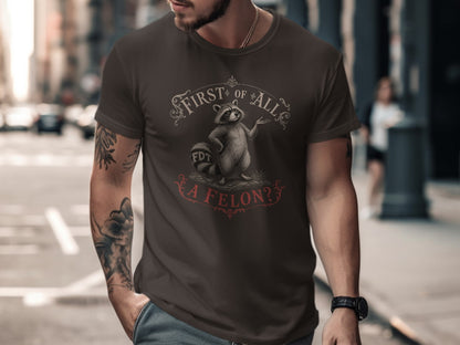 Dark brown t-shirt with "First of All, a Felon?" text and cartoon raccoon.