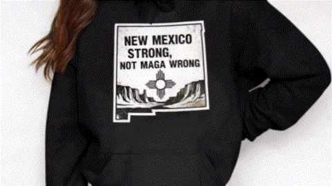 A person wearing a black hoodie with a graphic design on the front that says "NEW MEXICO STRONG, NOT MAGA WRONG".