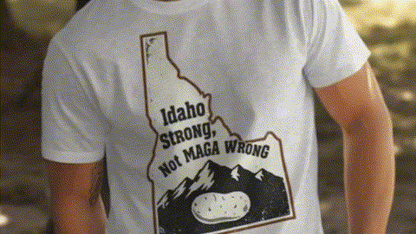 A white t-shirt with a graphic design depicting the state of Idaho and the text "Idaho Strong, Not MAGA Wrong".