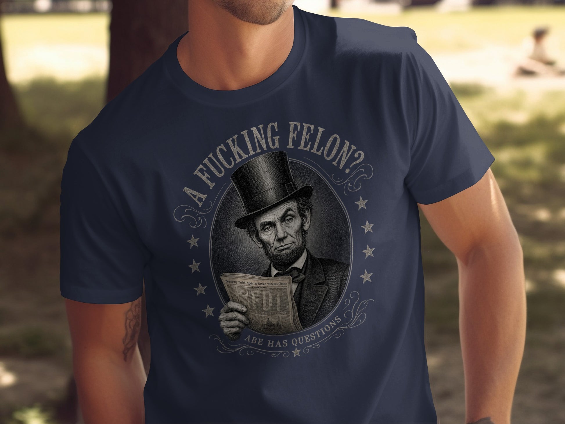 Abraham Lincoln graphic on a navy t-shirt with text "A Fucking Felon? Abe Has Questions."